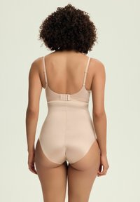 Nude modelująca bielizna z regulowanymi ramiączkami, z zapięciem na hak i oczko oraz gładką fakturą. Zaprojektowana z wysokim krojem nogawek i bezszwowym tyłem.