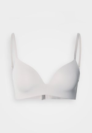 White seamless bra with soft fabric, molded cups, adjustable thin straps, and a hook-and-eye closure at the back.