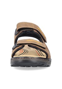 Sandale en cuir marron avec deux sangles Velcro réglables, semelle intérieure rembourrée, semelle en caoutchouc noir et motif de vagues coloré sur la semelle intérieure.