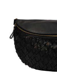 Svart lädercrossbody-väska med vävt mönster, guldfärgad dragkedja och liten läderdragkedjehängare.