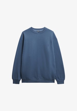 Sudadera azul hecha de una mezcla de algodón, con cuello redondo, mangas largas y un pequeño logo bordado en el pecho. Textura suave.