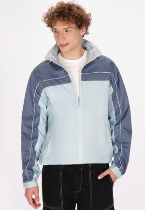 Lightweight, zippered jacket featuring a color-block design in light blue and navy, with a high collar and elastic cuffs.