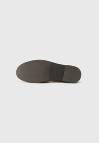 Brown leather shoe sole with a smooth, rounded shape, featuring a textured black rubber outsole and subtle branding on the heel.