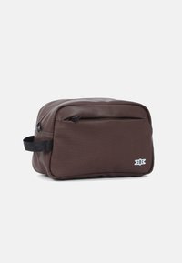 Braune, rechteckige Tasche aus strapazierfähigem Stoff mit einer vorderen Reißverschlusstasche, einem seitlichen Tragegriff und einem weißen Logo-Akzent.