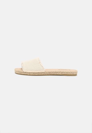 Sandalia de diapositiva beige con suela tejida y una amplia correa de tela texturizada, diseñada para uso casual.