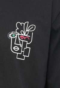 Αφηρημένη τέχνη με λευκές γραμμές που απεικονίζει ένα πρόσωπο με πράσινα και κόκκινα μάτια και σχήματα που μοιάζουν με φύλλα σε μαύρο ύφασμα, θυμίζοντας μοντέρνο κυβιστικό στυλ.