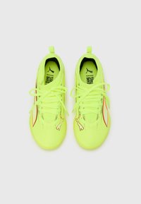 Scarpe sportive giallo neon con tomaia strutturata, dotate di lacci, un logo discreto e un accento arancione a contrasto lungo il lato.