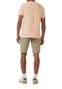 Lichtroze katoenen t-shirt met korte mouwen, gecombineerd met olijfgroene denim shorts, aangevuld met wit en marineblauwe sneakers.