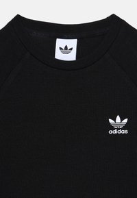 Fekete bordázott póló kerek nyakkal. A bal mellen található egy fehér Adidas trefoil logó. Puha szövettextúra.