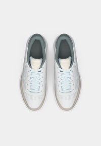 Jasnoniebieskie sneakersy Reebok z gładkiej skórzanej cholewki, perforowanym noskiem i neutralnymi szarymi akcentami. Posiadają płaskie sznurowadła i wyściełaną kołnierz.