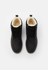 Botas negras con cordones, con un material exterior suave, forro de forro polar, punta redonda y costuras reforzadas. Cuenta con una lengüeta para facilitar el uso.