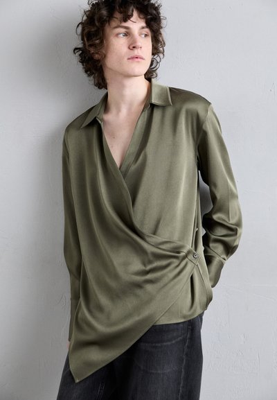 Olivgrünes Wickelhemd mit tiefem V-Ausschnitt, übergroßem Kragen und Knopfakzent an der Seite. Glatte Textur, lange Ärmel und lockere Passform.