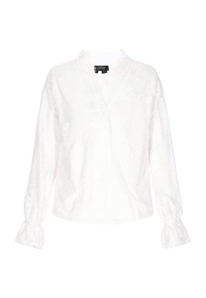Blouse blanche à manches longues, col en V et poignets froncés. Présente un motif floral texturé sur un tissu léger.