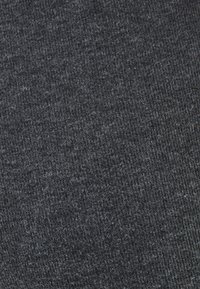 Donkergrijze stof met een geribbelde textuur, met fijne vlekjes lichtere draden door het hele materiaal. Zacht en rekbaar materiaal, lichtgewicht uitstraling.