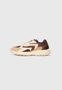 Lave sneakers med lav profil i beige, brun og creme mesh og ruskind, polstret creme sål og snørelukning på ensfarvet baggrund.