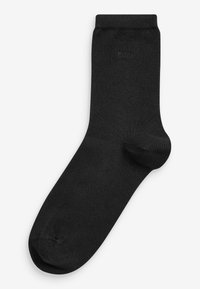 Sort bomuldsstrømpe med ribbet top, glat tekstur, forstærket tå og minimal branding nær toppen. Standard ankellængde.