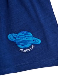 Tela azul con un diseño bordado de un planeta azul similar a Saturno con anillos y el texto "M. ROD101" debajo.