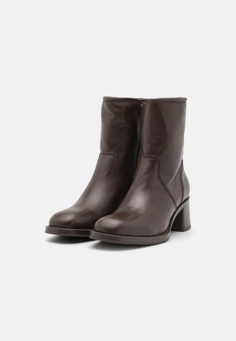 Braune Leder-Stiefeletten mit glatter Textur, runder Zehenpartie und klobigem Absatz. Seitlicher Reißverschluss für ein einfaches Anziehen. Schlichtes, klassisches Design.