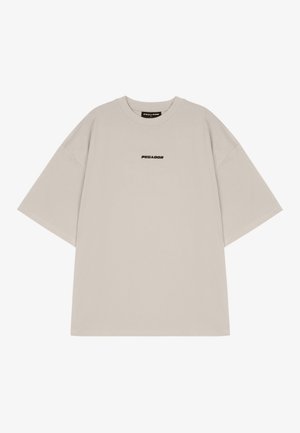 Short-sleeve, oversized t-shirt in light beige cotton. Features a small black "PEGAADOR" logo centered on the chest.
