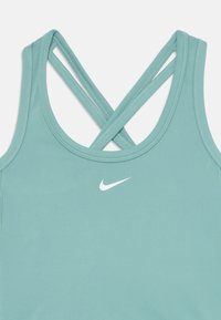 Jasnoniebieski sportowy top na ramiączkach z wycięciem na plecach, z krzyżującymi się ramiączkami i białym logo Nike z przodu. Gładka faktura.