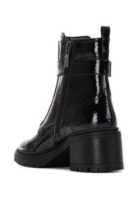 Botas de tobillo de charol negro con un acabado texturizado, cremallera lateral y tacón bloque. Cuenta con una correa alrededor del tobillo para mayor soporte.