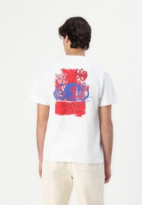 White cotton t-shirt featuring a colorful graphic print of an octopus and floral elements in red and blue on the back.