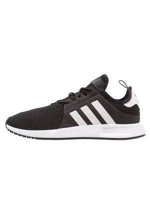 Baskets Adidas noires avec trois bandes blanches, languette de talon blanche, lacets noirs et semelle blanche, vues de profil latéral tournées vers la gauche.