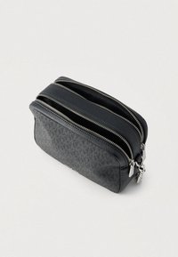 Czarna kosmetyczka z teksturowanej skóry z dwoma zamykanymi na suwak kieszeniami. Posiada srebrne okucia i prostokątny kształt.