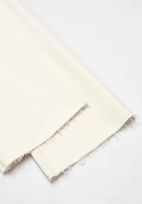 Tela de color crema con una textura suave, que presenta bordes deshilachados y un corte recto. Adecuada para diversos proyectos de costura.