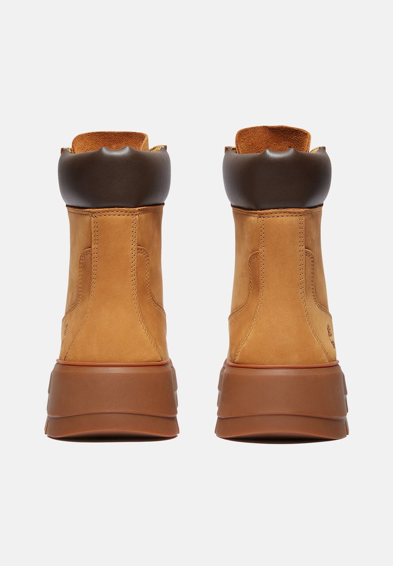 Stivali alla caviglia in pelle marrone chiaro con colletto imbottito in marrone, forma arrotondata e suola in gomma, caratterizzati da cuciture visibili e una finitura testurizzata.