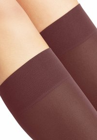 Burgunderfarbene Oberschenkelhohe Strümpfe mit einem strukturierten Rippband oben, darunter das glatte, durchsichtige Material, das nach unten verläuft.