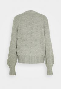 Pull en tricot vert clair avec des motifs en relief, ourlet et poignets côtelés, encolure arrondie et manches allongées.