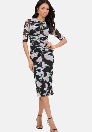 Abito floreale nero con motivo di fiori rosa e verdi, design aderente, texture arricciata, maniche trasparenti a tre quarti, lunghezza al ginocchio, abbinato a sandali neri con cinturini.