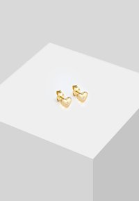 Goldene, herzförmige Steckerohrringe mit einem kleinen Akzent aus Zirkonia im Zentrum. Polierte Oberfläche und sichere Klappverschluss.