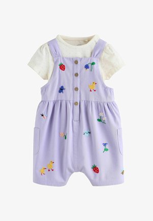 Lilla romper med knapper, broderede jordbær, blomster og dyr, båret over en cremefarvet polkaprik kortærmet skjorte.