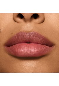 Rouge à lèvres mat dans une teinte rose douce, mettant en valeur des lèvres pulpeuses et lisses avec une texture subtile et une finition naturelle sur un teint chaud.