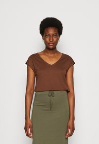 Brown, short-sleeve V-neck top paired with a green, drawstring waist skirt. Soft fabric with a relaxed fit, minimal design.