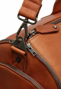 Borsa in pelle marrone con superficie texture, zip metallica, accessori a clip e tracolla imbottita. La cucitura dettagliata è visibile.