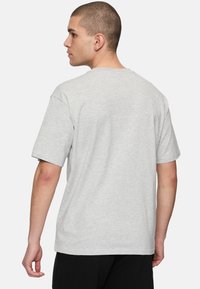 Camiseta de algodón gris con mangas cortas, cuello redondo estándar y un corte relajado. El material parece suave y ligero.