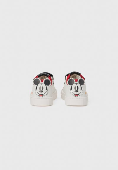 Weiße Sneaker mit schwarzen Fersen und Mickey Mouse Gesichtsgraphic auf der Rückseite. Texturierte Gummisohlen mit roten Akzenten und Nähten.