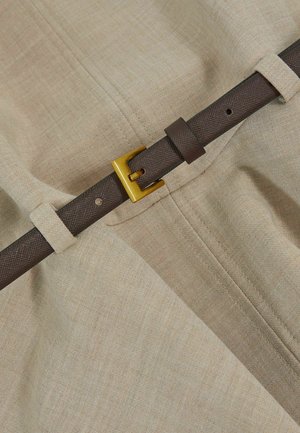 Beige stof met een fijne textuur heeft een bruine geweven riem en een gouden metalen gesp, die is beveiligd met een stoffen lus voor aanpassing.