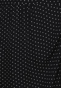 Tecido preto com bolinhas brancas, apresentando um design pregueado. Textura suave, material leve e um padrão clássico por todo o tecido.