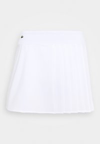 Bílá plisovaná sukně s šortkami vyrobená z lehké tkaniny, s páskem zdobeným logem. Design je krátký a sportovní, vhodný pro aktivní nošení.