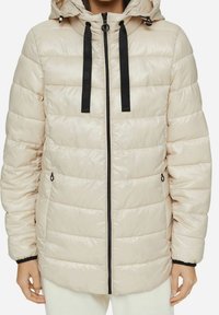 Chaqueta acolchada color beige con un acabado brillante, puños elásticos, cremallera frontal y capucha desmontable con cordones negros.