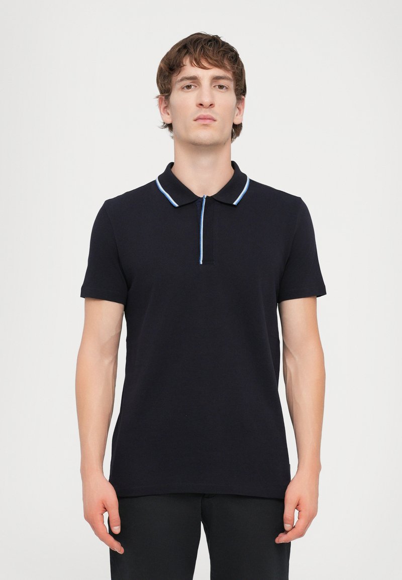 Polo de cor azul marinho escuro com mangas curtas, um colarinho e um detalhe azul claro no colarinho. Feito de um tecido texturizado, com um design ajustado.