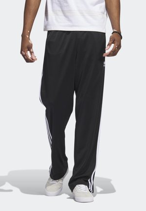 Svarta träningsbyxor av lätt tyg med vita sidostripes, lös passform och elastisk midja för komfort.