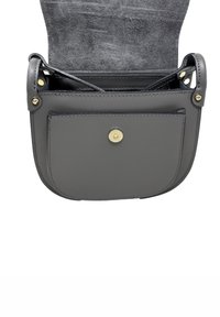 Borsa a tracolla in pelle grigia con tasca frontale chiusa da un bottone di ottone rotondo e fodera interna in suede visibile.