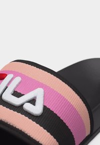 Μαύρο σανδάλι με φαρδιά υφασμάτινη λουρίδα σε ροζ, ροδακινί και μαύρες ρίγες, με ανάγλυφη λευκή επιγραφή λογότυπου.