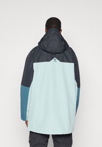 Kurtka z kapturem z kolorowym blokiem w jasnoniebieskim, ciemnoszarym i morskim kolorze. Wykonana z trwałego materiału o gładkiej fakturze.