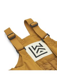 Braune gepolsterte Latzhosen mit verstellbaren Trägern, schwarzem Zubehör und einem Logo-Patch mit geometrischem Design auf einem cremigen Hintergrund.